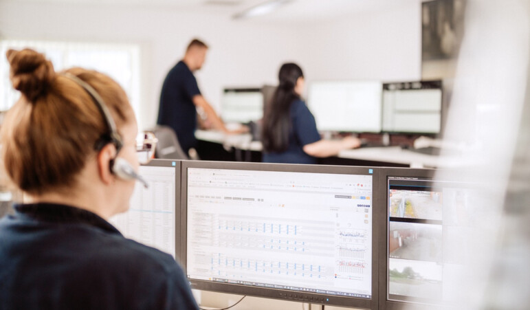 Security employee monitors screens in alarm receiving center