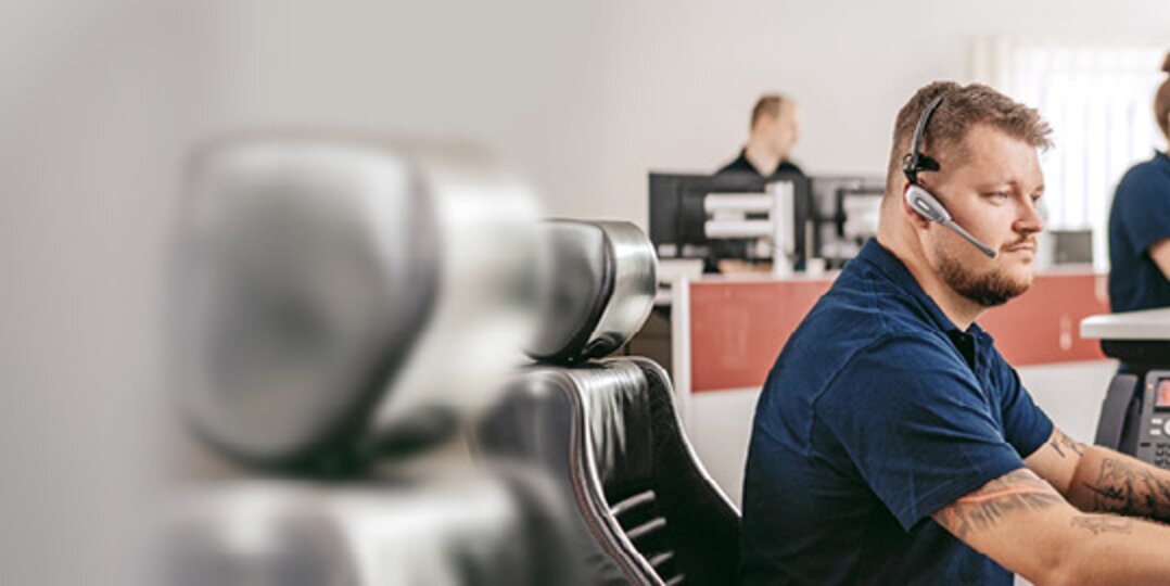 Man with headset looking at a monitor