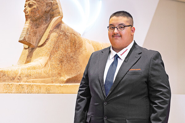 Dussmann trainee smiling while standing in front of a sphinx sculpture. 