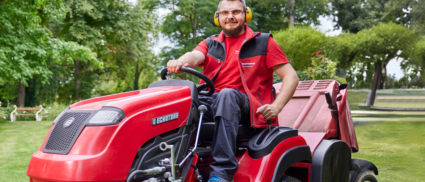 Dussmann employee from the green and grounds maintenance department on a lawn mower.