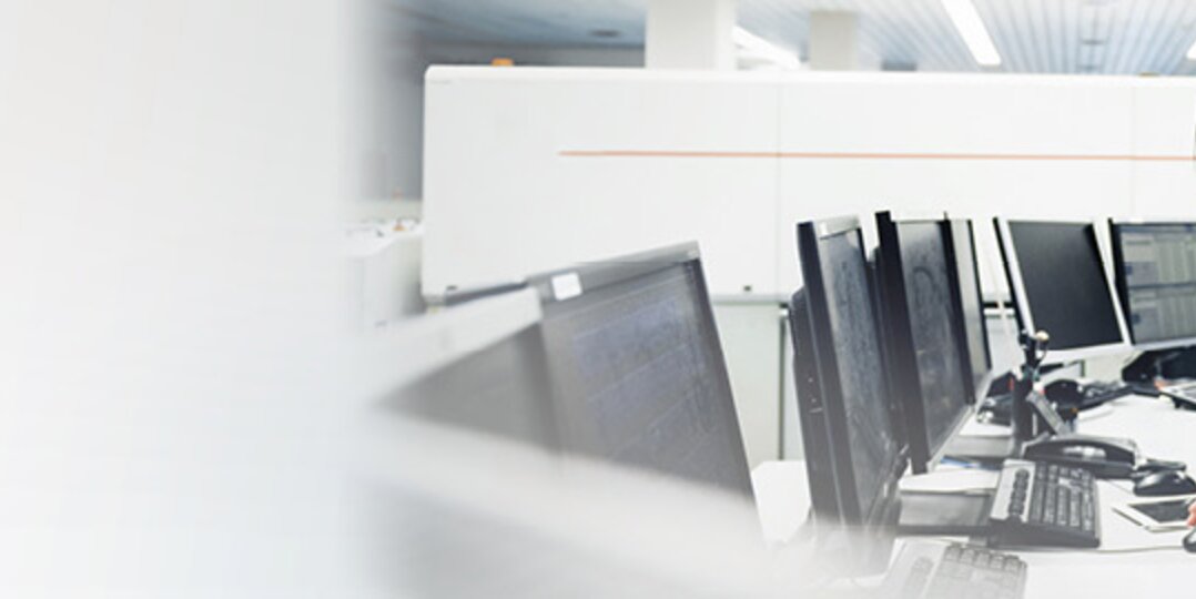 Two smiling Dussmann employees working together in an open-plan office. 