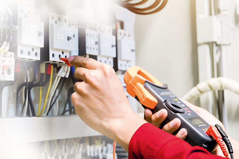 A technician operating a meter in a wired room. 