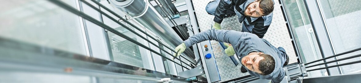 Two Technicians repair glass elevator